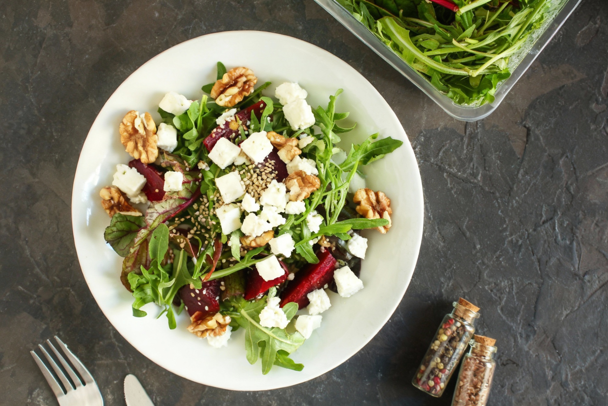 Sałatka z buraków, fety i orzechów włoskich z rukolą na białym talerzu